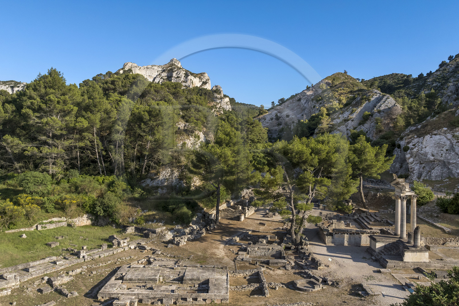 France, Bouches du Rhone, Regional Natural Park of the Alpilles, Saint Remy de Provence, site archéologique de Glanum at the foot of the Alpilles massif, reconstructed columns and entablature of the small twin temple of the first forum in the foreground on the right (aerial view)