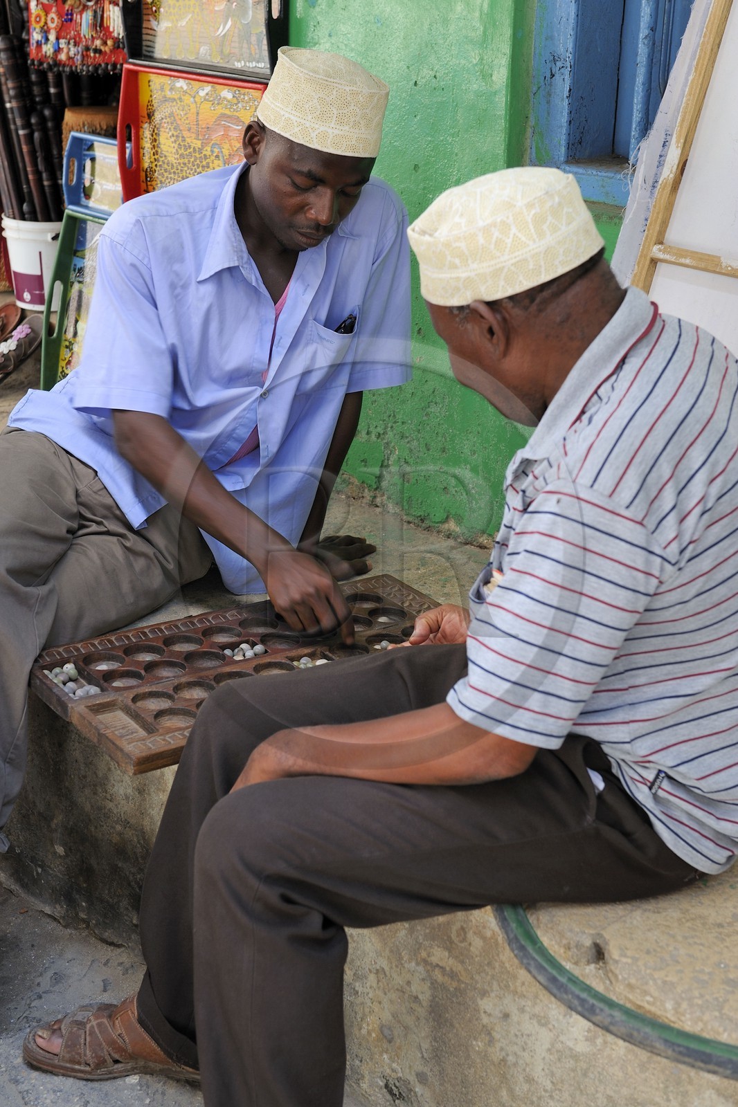 Tanzanie, archipel de Zanzibar, île de Unguja (Zanzibar), ville de Zanzibar, quartier Stone Town, classé Patrimoine Mondial de l' UNESCO, deux hommes entrain de jouer au jeu traditionnel d'Afrique l'Awale dans une ruelle de la vieille ville dans le quartier de Shangani