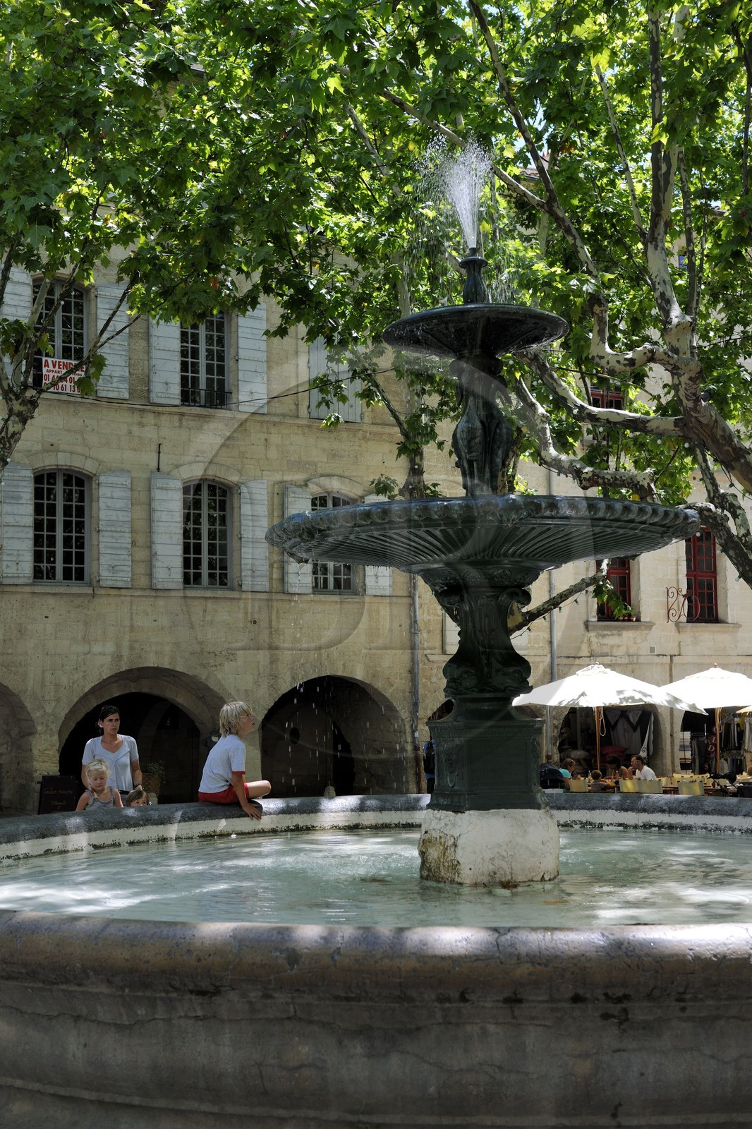 France, Gard (30), Uzès, classée ville d'art et d'histoire, fontaine de la Place aux Herbes entourée de maisons à arcades et ses terrasses de café