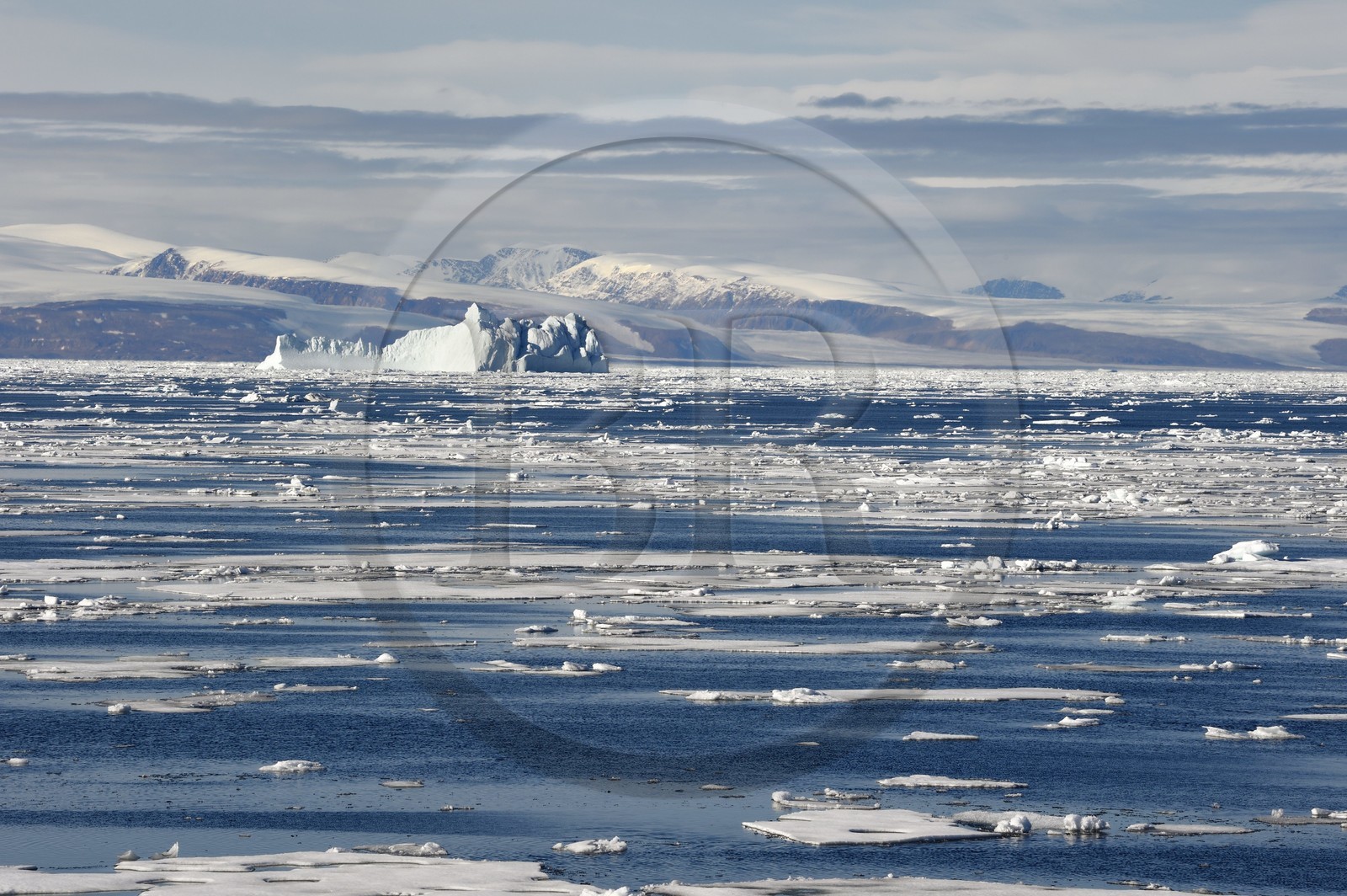 Greenland, North West coast, Smith sound north of Baffin Bay, broken pieces of Arctic sea ice and giant iceberg in the background towards the Canadian coast of Ellesmere Island
