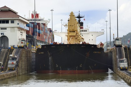 Panama, Canal de Panama, écluses de Miraflores, mules mécaniques ou locomotives électriques guidant un cargo Panamax entre les murs de l'écluse
