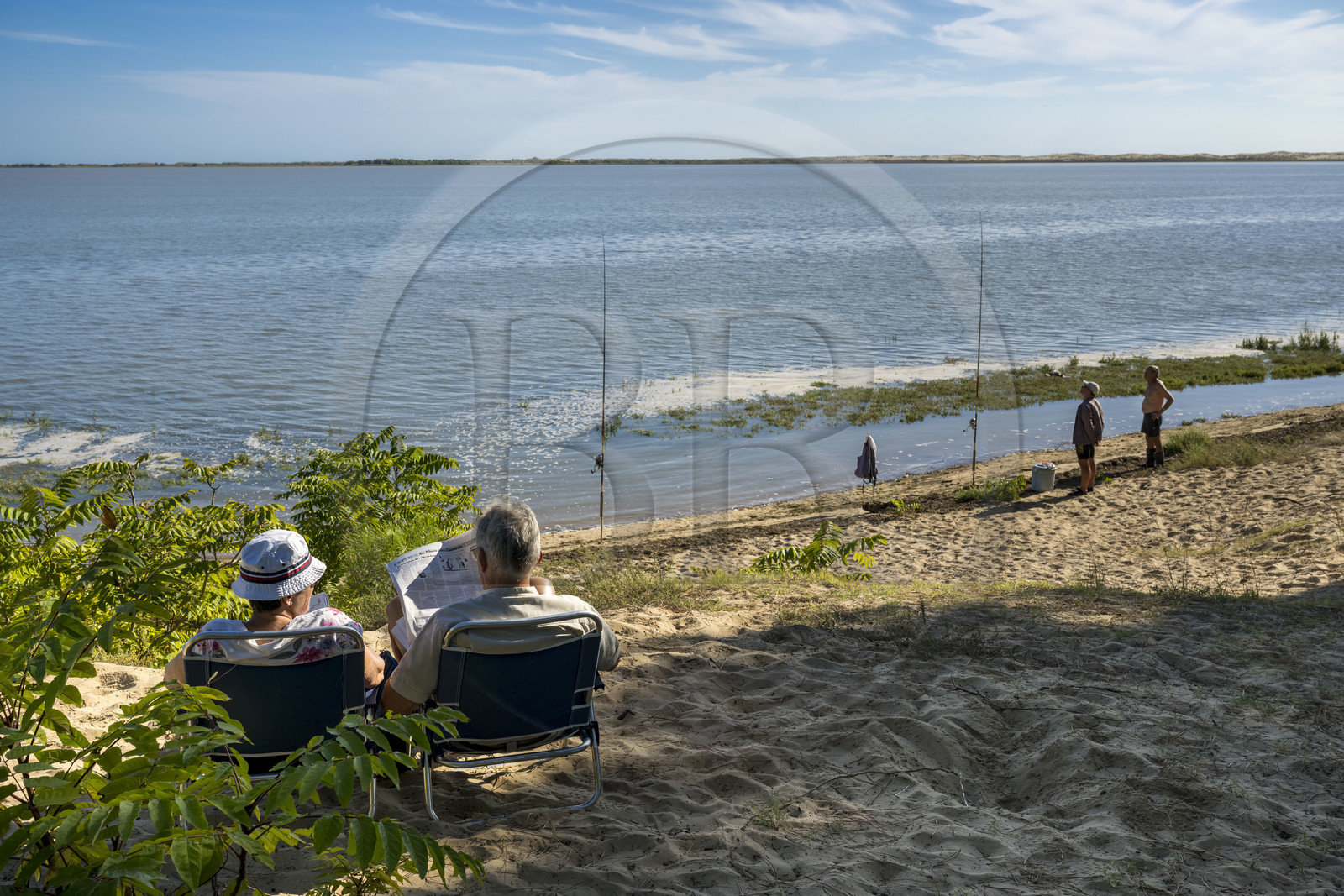 France, Charente-Maritime (17), Royan, Les Mathes, pecheurs à la ligne en bordure de la baie de Bonne Anse à marée haute et lecture du journal
