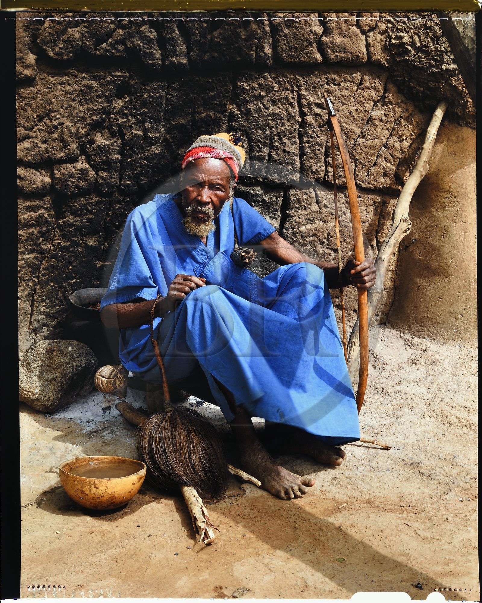 Burkina Faso, province de Poni, pays des Lobi, région de Loropéni, chef du village de Ouadara posant avec ses attributs (arc et flèches, chasse-mouches) et une calebasse de bière de mil (céréale)