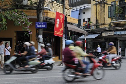 Vietnam, Hanoi, motorcycle traffic in the old city and Ho Chi Minh poster