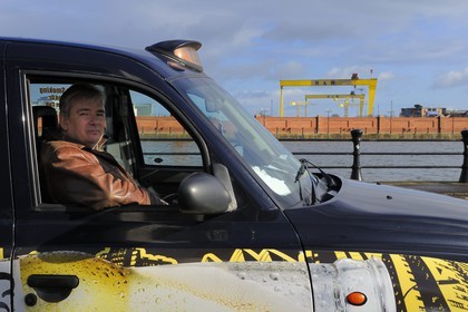 Royaume-Uni, Irlande du Nord, Belfast, Billy Scott dans son Black Cab devant les deux portiques de Harland and Wolff surnommés Samson et Goliath qui sont devenus un repère de la ville