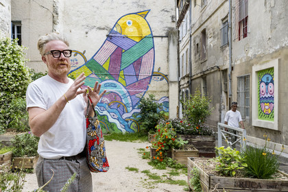 France, Vaucluse, Avignon, Graffiti artist Pablito Zago in front of the bird mural he created, founder of the Cartel association and the Shed workshop