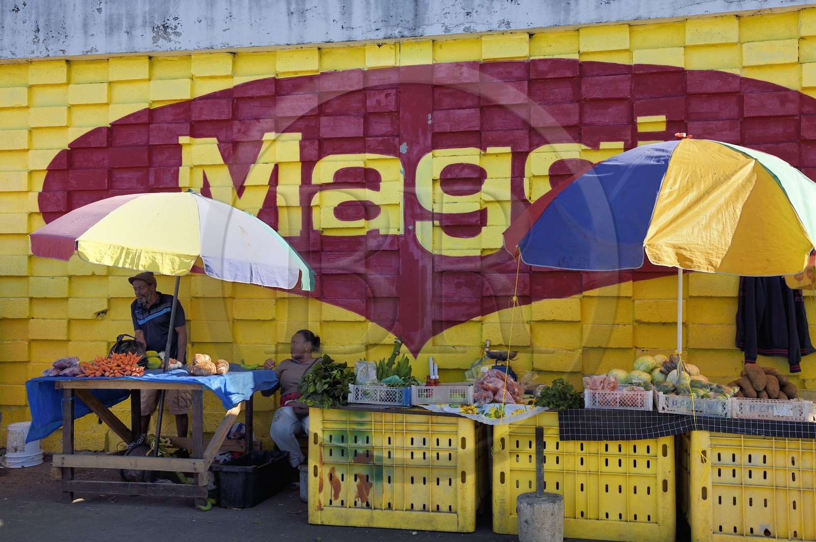 Caraïbes, Ile de la Dominique, la capitale Roseau, marché centrale, étal de fruits et légumes devant une peinture murale publicitaire pou Maggi