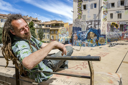 France, Bouches-du-Rhône (13), Marseille, quartier du Panier, peintures murales et graffitis place du Refuge, le street artiste Loïc Perrel dit Poasson pose devant la fresque de l'enfant footbaleur et de la femme qu'il a réalisé en arrière plan