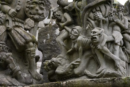 France, Finistère (29), Guimiliau, le calvaire dans l'enclos paroissial, selon la légende la jeune servante katell Gollet est vouée au flammes éternelles car elle aurait dissimulé ses écarts de conduite en confession et commis le sacrilège de dérober une hostie consacrée qu'elle a offerte à Satan qui se cachait sous les traits de son amant