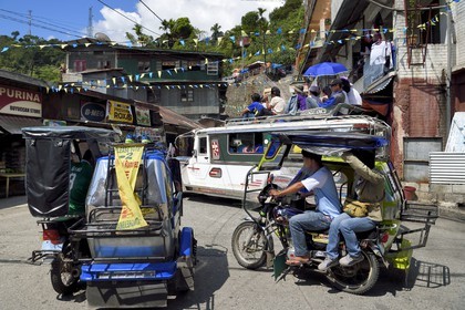 Philippines, province d'Ifugao, ville de Banaue, jeepney (jeep allongée pour le transport de passagers) et tricycle moto-taxi sur la place principale, passagers sur le toit