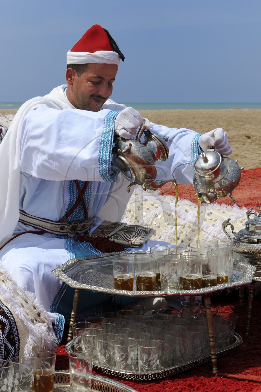 Maroc, région de l'Oriental, service du thé à la menthe en costume d'apparat sur une plage