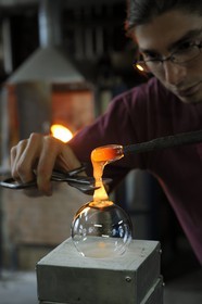 France, Moselle (57), Meisenthal, Thibaut souffleur au Centre international d’Art verrier (CIAV), fabrication d'une boule de Noël en verre. Avec du verre en fusion, il colmate directement le trou – l’impact où la boule a été soufflée