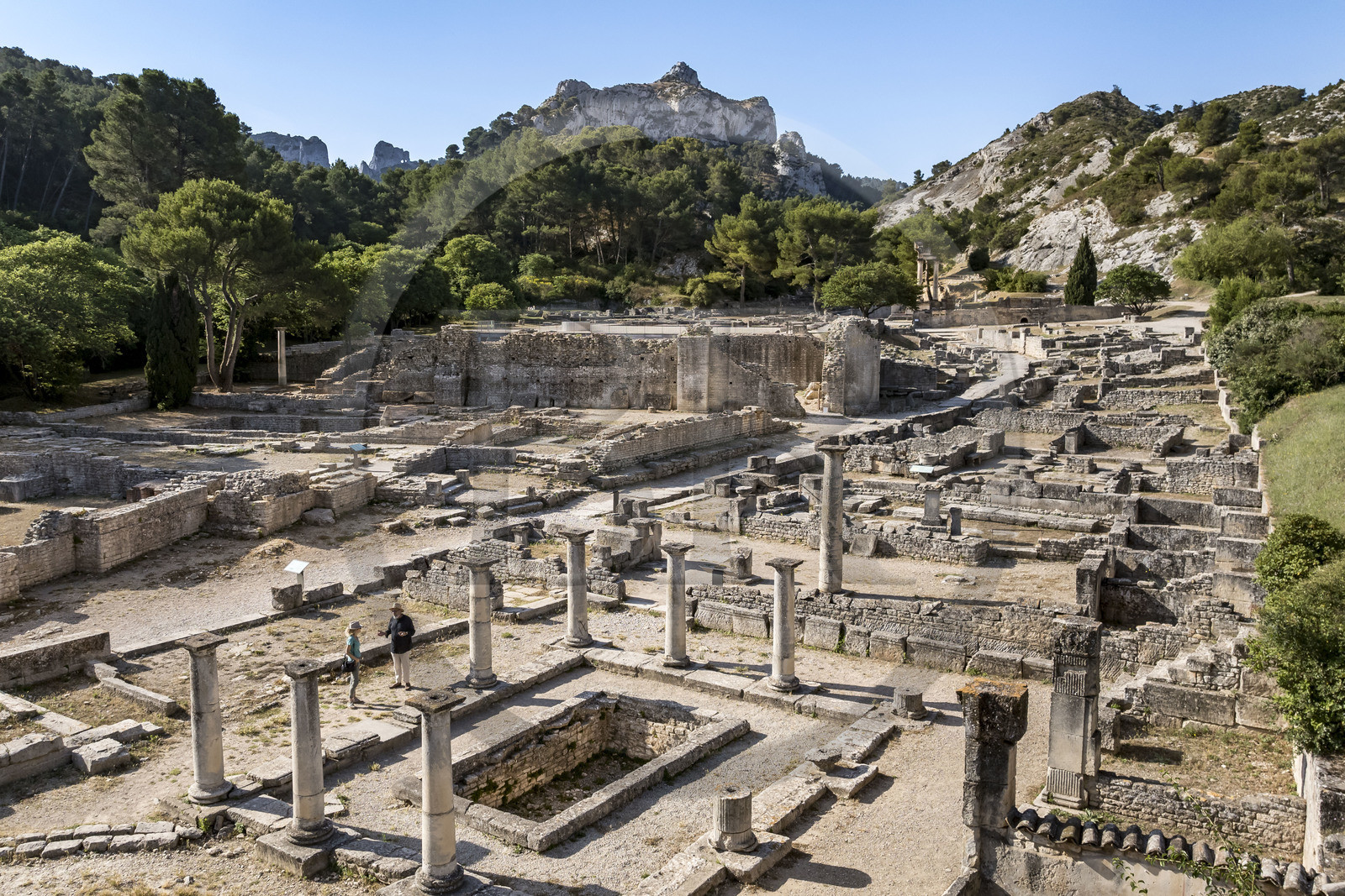 France, Bouches du Rhone, Regional Natural Park of the Alpilles, Saint Remy de Provence, site archéologique de Glanum at the foot of the Alpilles massif, Bernard Le Magouarou, administrator of the archaeological site, presents the house of Antes with peristyle and basin in the foreground on the right (aerial view)