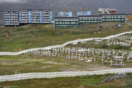 Groenland, région du centre ouest, Sisimiut (autrefois Holsteinsborg), le cimetière, les cercueils sont déposés en surface puis recouverts de pierres ou de ciment, le sol ne pouvant être creusé, les tombes sont ensuite décorées avec des fleurs artificielles, logement social en arrière-plan