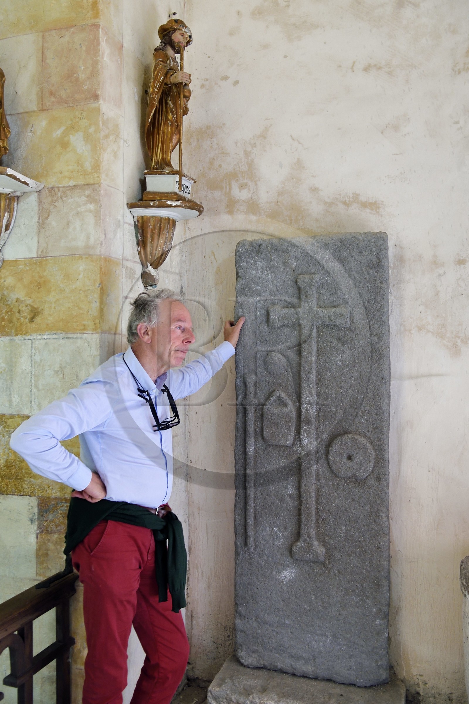 France, Cantal (15), étape sur le chemin de Saint-Jacques de Compostelle par la Via Arverna, Neussargues-Moissac, église Saint-Hilaire du XIIe siècle, tombe d'un pélerin du XVIIe siècle ayant effectué le chemin de St Jacques de Compostelle, dalle funéraire avec le bourdon, le sac et la coquille autour de la croix funéraire, le conservateur en chef du patrimoine Humbert Jacomet