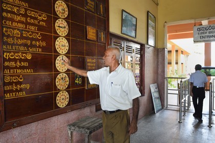 Sri Lanka, Province du Sud, gare de Galle, employé de la gare réglant le tableau d'affichage des horaires