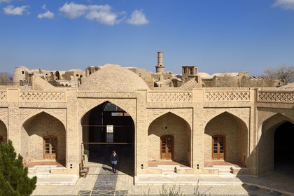 Iran, Yazd province, edge of the Dasht-e Kavir desert, Kharanaq old village, the caravanserai dating from the time of the Qajar dynasty and the oscillating minaret in the background