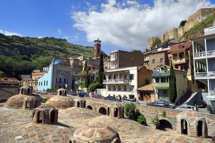 Georgia, Tbilisi, Old City, thermal district of Abanotoubani with the roofs of public sulfur baths, the Orbeliani Baths with the blue tiled facade, the minaret of the mosque and the Narikala fortress (4th century) in the background