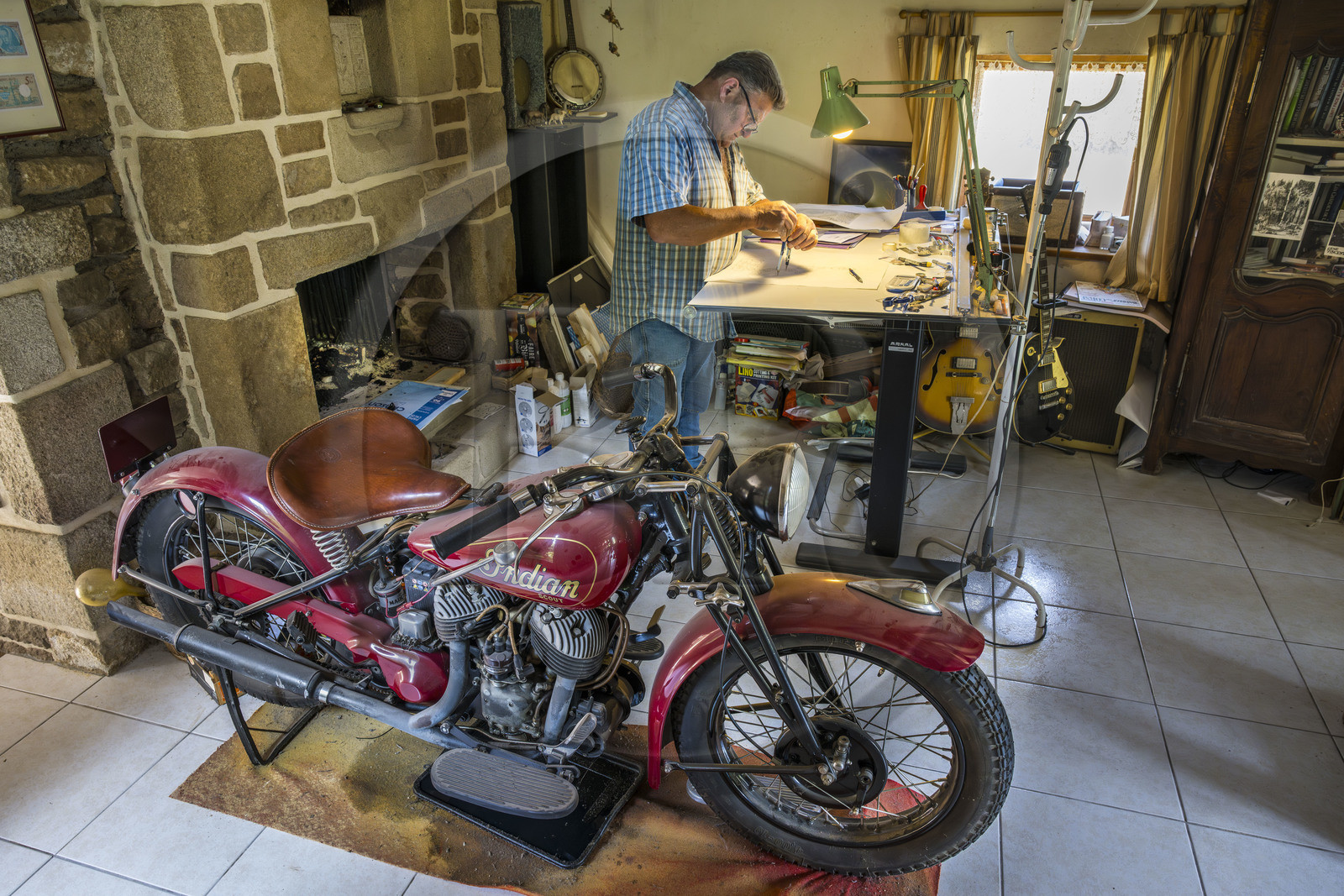 France, Morbihan (56), Locoal-Mendon, le sculpteur et tailleur de pierre Gueho Patrick dans son bureau avec une moto Indian scout de 1940