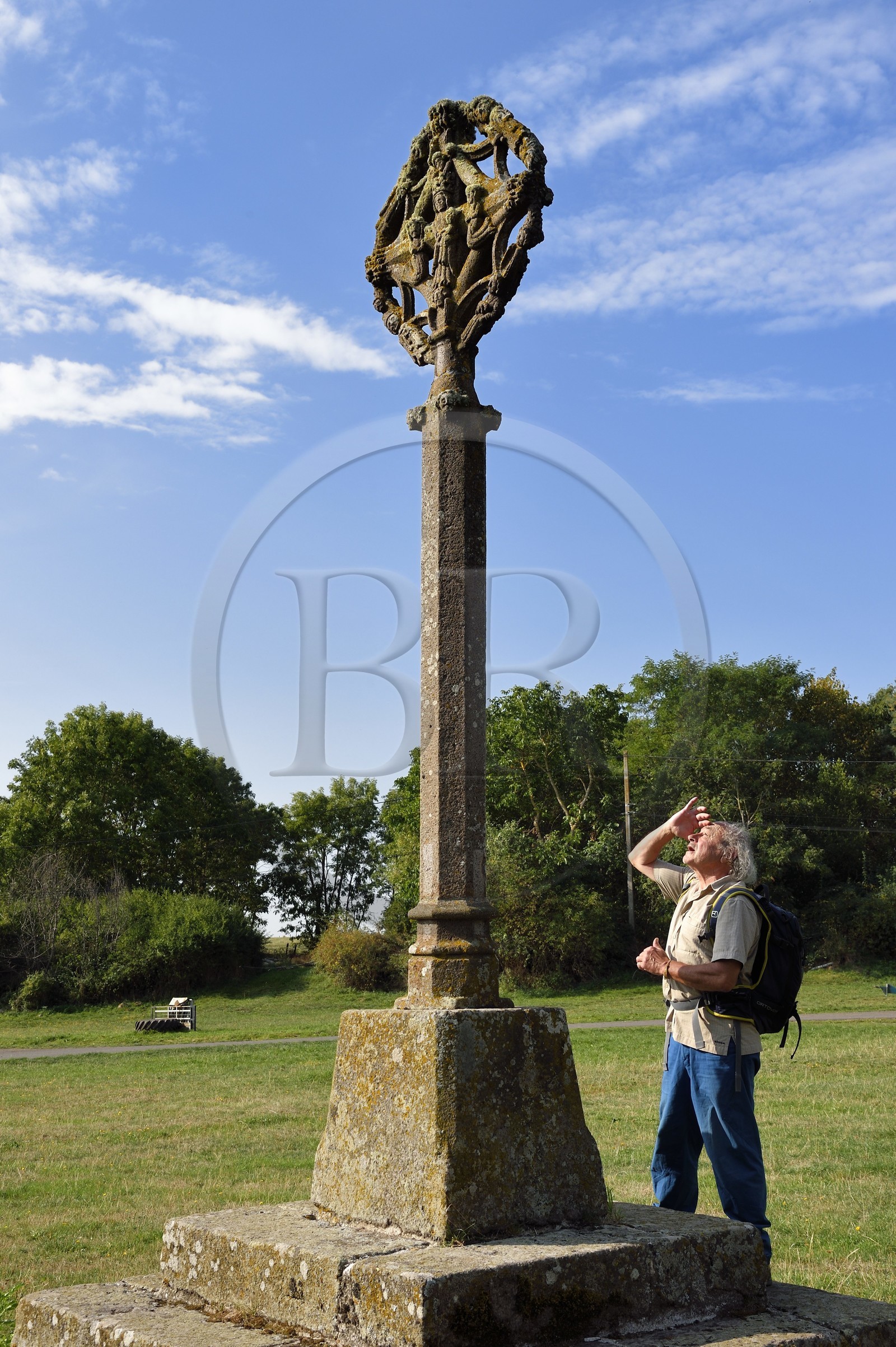 France, Cantal (15), Parc Naturel Régional des Volcans d'Auvergne, randonneur sur le chemin de Saint-Jacques de Compostelle par la Via Arverna, Chalinargues, la Croix de Mons du XVe siècle en granit, de ce coté on peut voir la Vierge entourée d'anges, de personnes agenouillés et de saints, de l'autre le Christ