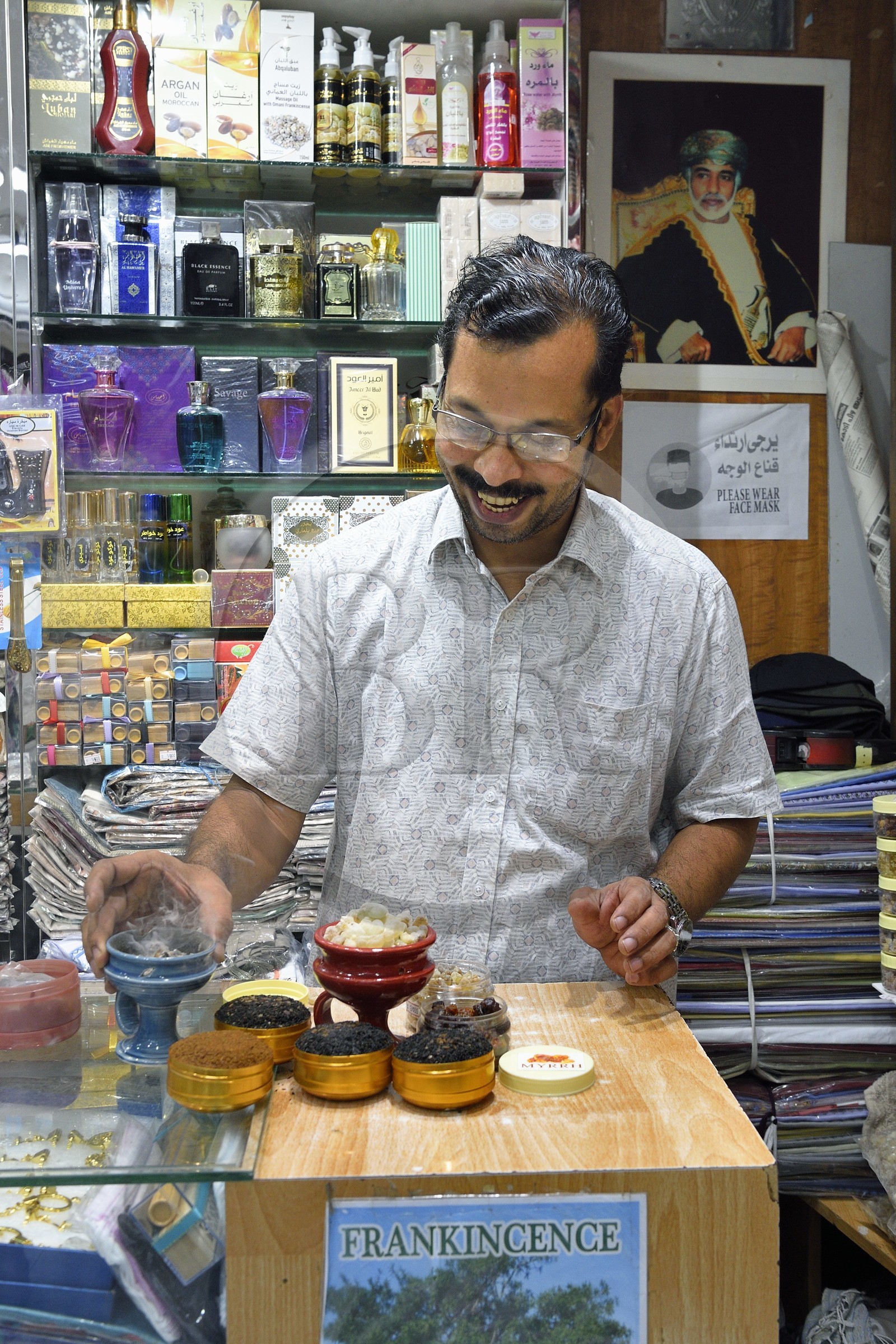 Sultanat d'Oman, Mascate, vieux Mascate, le souk de Muttrah, le vendeur Fathima Bint Abdan Bin Hassan faisant bruler de l'encens pur, portrait du Sultan Qabus décédé en 2020 en arrière plan