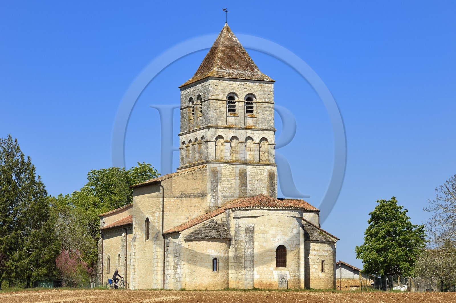 France, Dordogne (24), Périgord Vert, Javerlhac-et-la-Chapelle-Saint-Robert, cycliste faisant la véloroute La Flow Vélo devant le chevet de l'église romane XIIème siècle de La Chapelle-Saint-Robert, église de l'ancien prieuré fondé par un disciple du premier abbé de la Chaise-Dieu Robert de Turlande