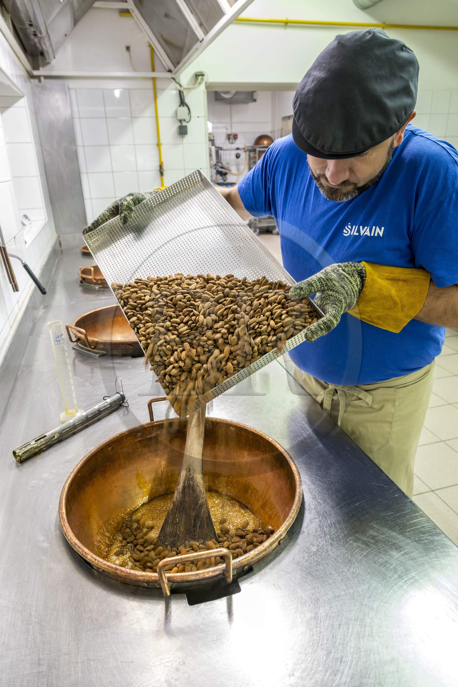 France, Vaucluse (84), Saint Didier, dans l'atelier de fabrication des Nougats Silvain, paysans nougatiers, Charles-Henri Bagnol confectionne une plaque de nougat noir, mélange des amandons grillés et de la base de miel caramélisé