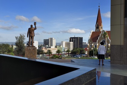 Namibia, Khomas region, Windhoek, Christ Church (or Christuskirche), Lutheran church designed by architect Gottlieb Redecker seen from the Independence Memorial Museum built by North Korea and statue of Dr Sam Nujoma (founding président of the Namibian nation)