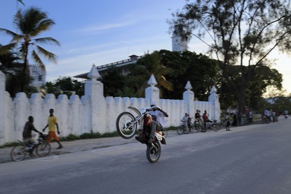 Tanzanie, archipel de Zanzibar, île de Unguja (Zanzibar), ville de Zanzibar, quartier Stone Town, classé Patrimoine Mondial de l' UNESCO, jeune homme frimant sur sa moto sur Mizingani street