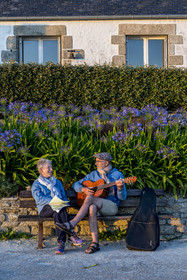 France, Finistère (29), Iles du Ponant, Ile de Batz, Remi joue de la guitare pour Françoise sur un banc de l'embarquadère en fin de journée