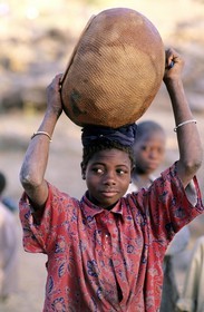 Mali, pays Dogon, falaise de Bandiagara classée Patrimoine Mondial de l'UNESCO, Tereli, jeune fille se rendant au puit, portant un canari (poterie)