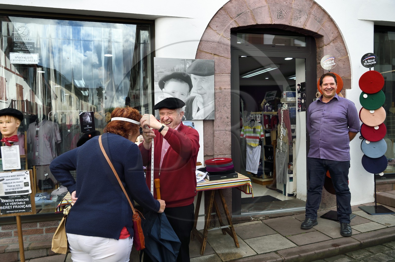 France, Pyrénées-Atlantiques (64), Pays-Basque, Saint-Jean-Pied-de-Port, rue d'Espagne sur le chemin de Saint-Jacques-de-Compostelle, l'ancien champion de pelote grand chistera Michel Cavier et son père Jean Cavier qui prend ici la mesure pour un béret devant leur boutique de vêtements