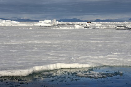 Groenland, cote Nord-Ouest, Smith sound au nord de la baie de Baffin, morceaux de glace de la banquise arctique en train de fondre et un PolarCirkel boat (zodiac) d'exploration du bateau de croisière MS Fram de la compagnie Hurtigruten, iceberg géant en arrière plan vers la côte canadienne de l'ile d'Ellesmere