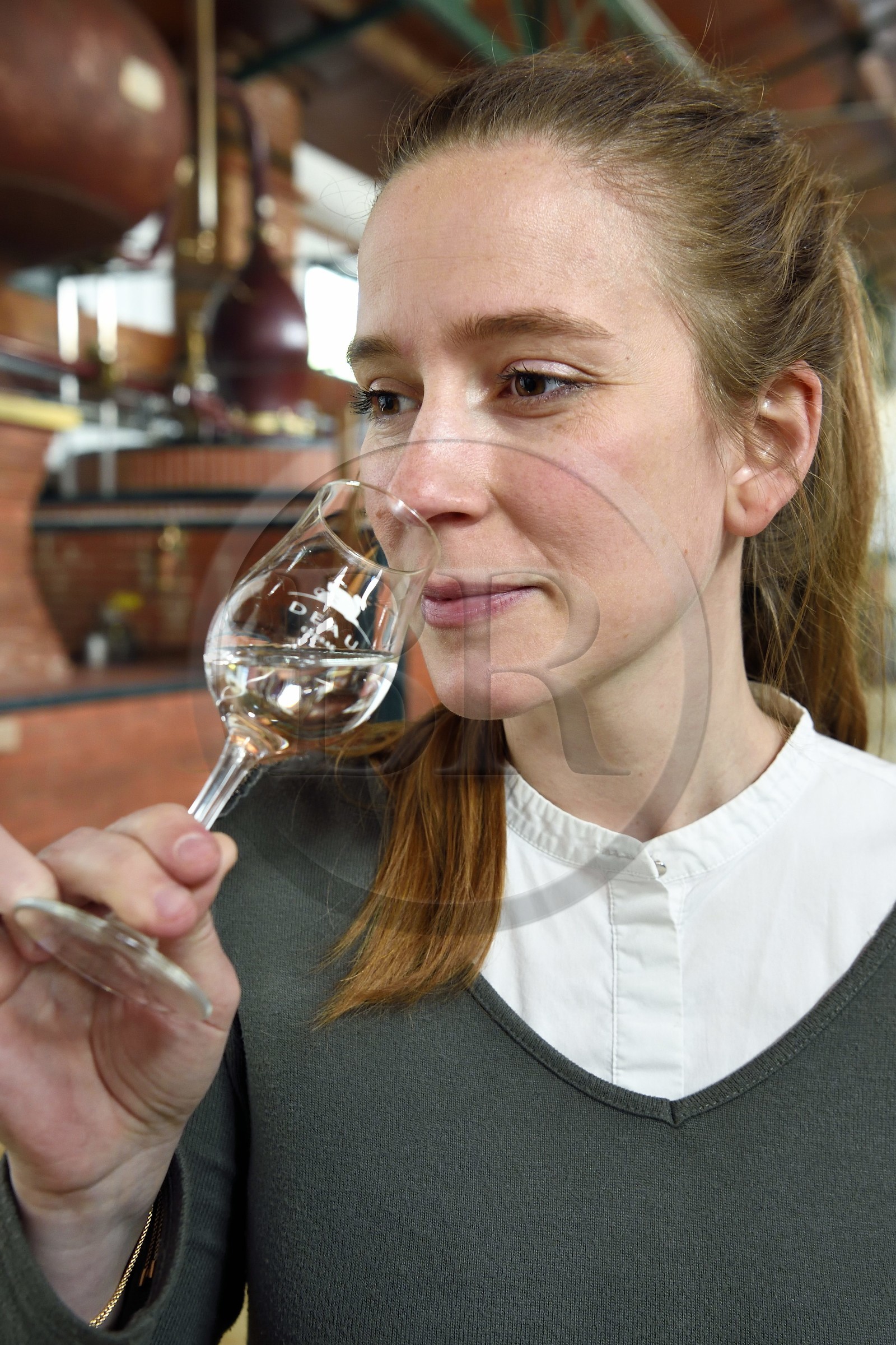 France, Charente (16), Sireuil, Distillerie des Moisans, la responsable du développement des activités commerciales Laurette Didière sent l'eau-de-vie de vin qui deviendra du cognac
