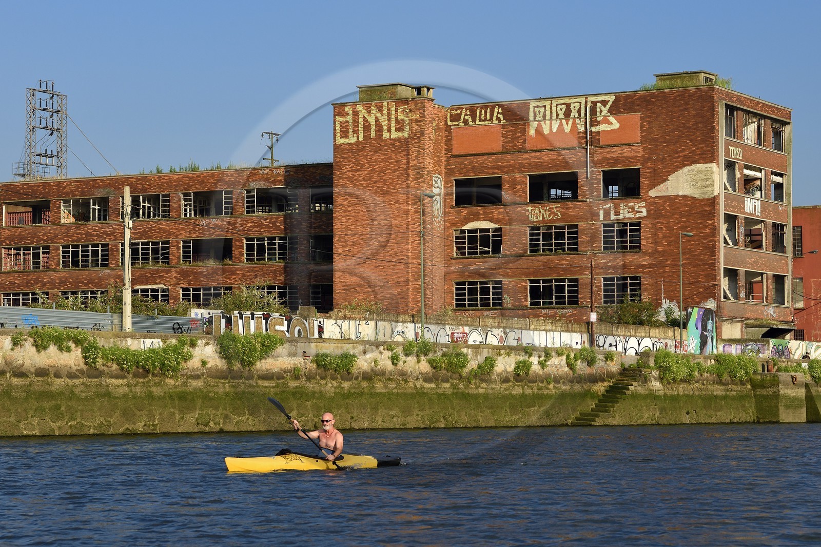 Espagne, Pays basque espagnol, Biscaye, Bilbao, kayakiste remontant le fleuve Nervion vers l'embouchure, friche industrielle de Deusto, ancien batiment industriel