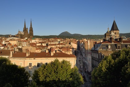 France, Puy de Dome, Clermont Ferrand, Rue du Port between Notre-Dame de l'Assomption cathedral on the left and Notre-Dame-du-Port basilica on the right, in the background the former volcano Puy de Dome