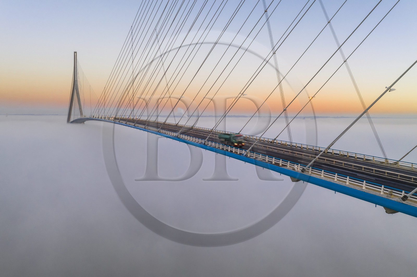 France, between  Calvados and Seine Maritime, the Pont de Normandie (Normandy Bridge) emerges from the morning mist of autumn and spans the Seine to connect the towns of Honfleur and Le Havre