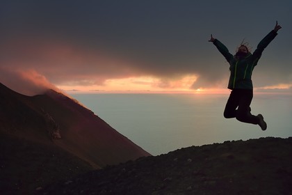 Italie, Sicile, iles Eoliennes, classées Patrimoine Mondial de l'UNESCO, ile de Stromboli, randonneur et fumerolles d'une éruption sur les pentes du volcan actif au coucher de soleil