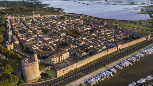 France, Gard (30), Aigues-Mortes, la ville médiévale entourée par ses remparts, la Tour de Constance et le port du canal du Rhône à Sète au premier plan, les marais salants (Salins du Midi) en arrière plan (vue aérienne)