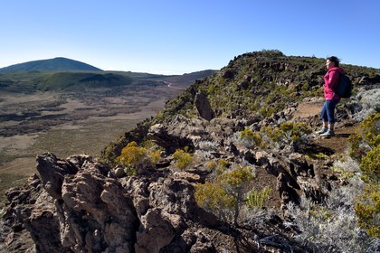 France, Reunion island (French overseas department), Reunion National Park listed as World heritage by UNESCO, on the slopes of the Piton de la Fournaise volcano, hiker on the Ste Therese oratory trail above the Plaine des Sables that we can see below