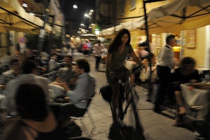 Italy, Lombardy, Milan, cyclist navigating between tables of restaurants terraces via Brera