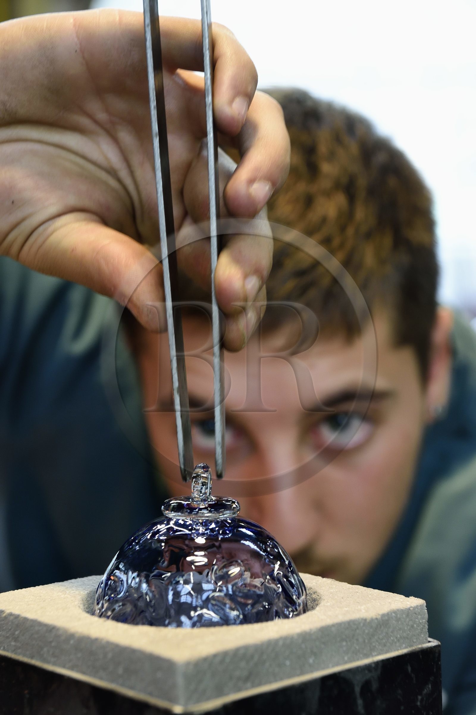 France, Moselle (57), Meisenthal, Centre international d’Art verrier (CIAV), l'atelier de soufflage, fabrication artisanale d'une boule de Noël, finalisation de la mise en place du crochet en verre