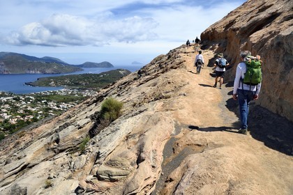 Italie, Sicile, iles Eoliennes, classées Patrimoine Mondial de l'UNESCO, ile de Vulcano, randonneurs dans l'ascension du cratère du volcan della Fossa, passage sur du tuf volcanique et l'Ile de Lipari en arrière plan
