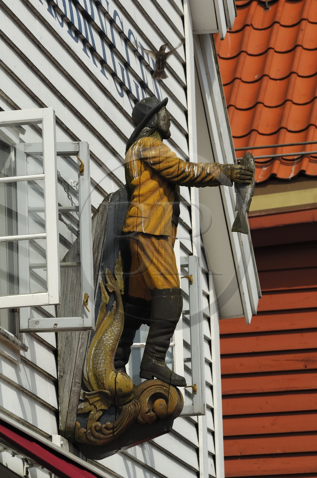 Norvège, Hordaland, Bergen, statue de pêcheur sur la facade d'une maison en bois