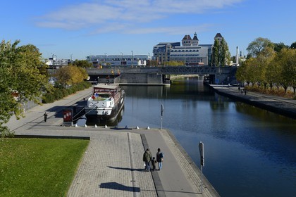 France, Paris (75), le canal de l'Ourcq dans le parc de la Villette et les anciens Grands Moulins de Pantin créées en 1884 réhabilités pour y réaliser un ensemble immobilier de bureauxen arrière plan