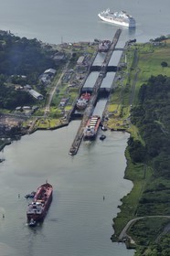 Panama, Colon province, Panama Canal, Gatun locks, Panamax cargo passing the locks, a cruise ship on Gatun Lake in the background (aerial view)