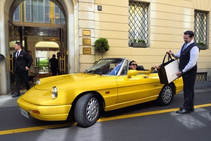 Italie, Lombardie, Milan, Quadrilatère de la Mode (Quadrilatero della moda), cabriolet Alfa Romeo Duetto Spider jaune devant le Four Seasons Hotel Milano, le portier amène un sac Gucci