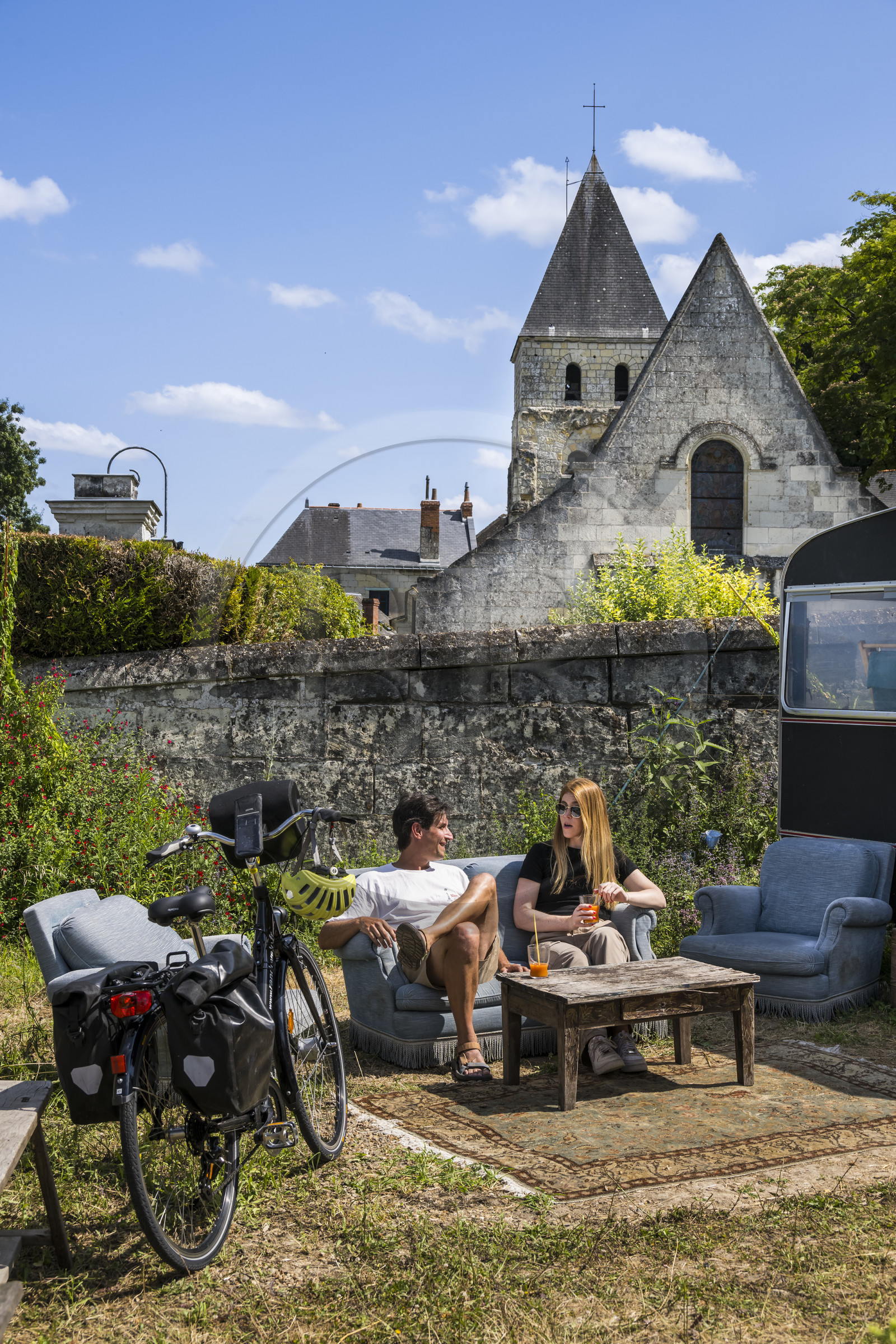France, Maine-et-Loire (49), vallée de la Loire classée au Patrimoine Mondial par l'UNESCO, Gennes-Val-de-Loire, randonnée à bicyclette sur les berges de la Loire, pause à la librairie-café L'Idiot de l'association Gabare And Co dans l'ancienne école des Filles de Chênehutte, l'église notre dame des tuffeaux en arrière plan