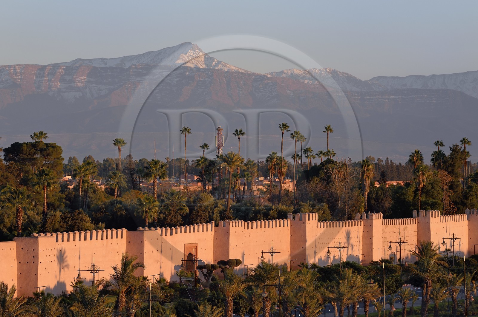 Morocco, High Atlas, Marrakech, Imperial city, Medina listed as World Heritage by UNESCO, the ramparts of the city and the Oukaïmeden summit in the snow-covered Atlas in the background at sunset