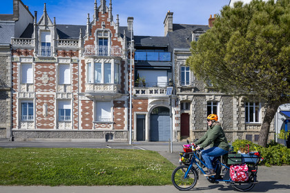 France, Loire-Atlantique, Saint-Nazaire, Boulevard du Président Wilson on the seafront, cyclist using a Velycéo with his dog passing in front of one of the houses spared by the bombings of the Second World War